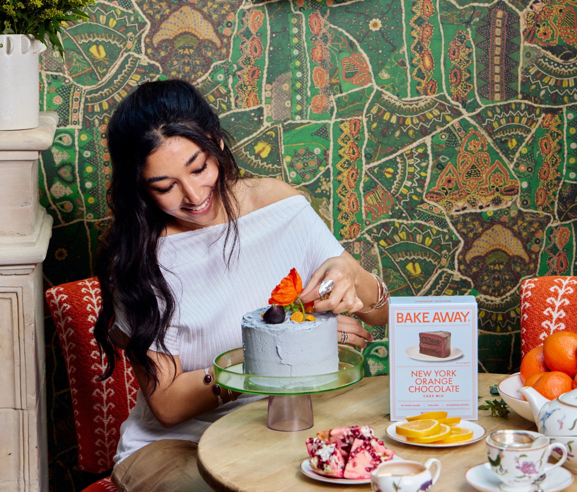 Woman decorating a cake with colorful flowers in a cozy setting.