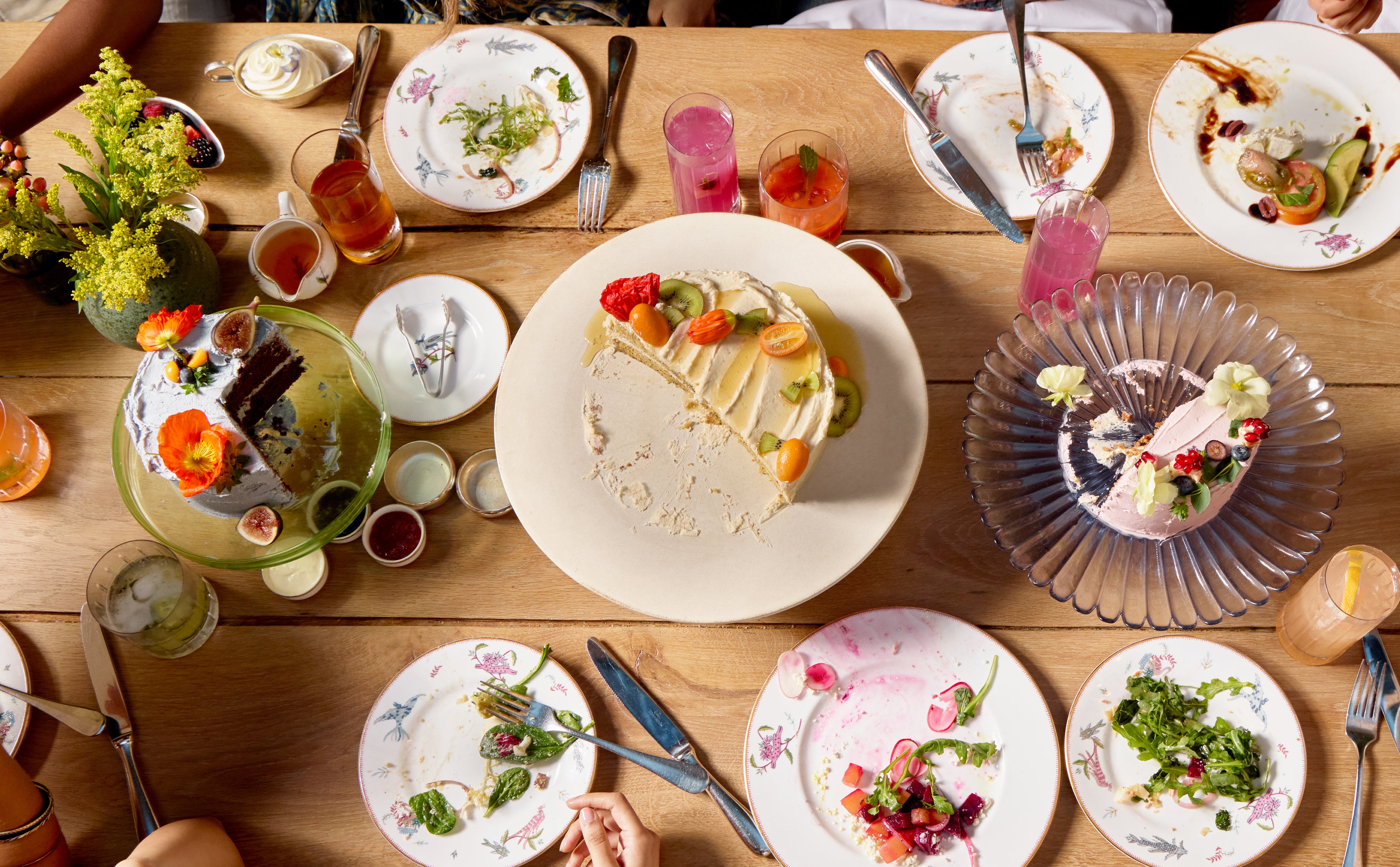 Dessert table with various plates of food and drinks on a wooden surface