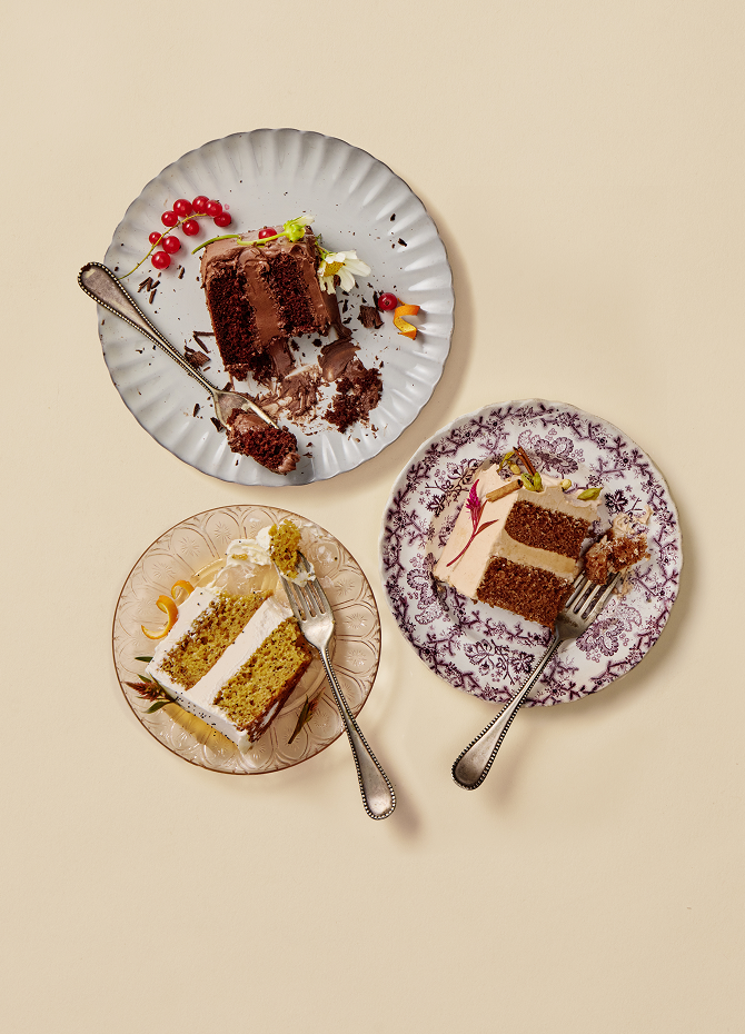 Three plates with slices of cake on a beige background