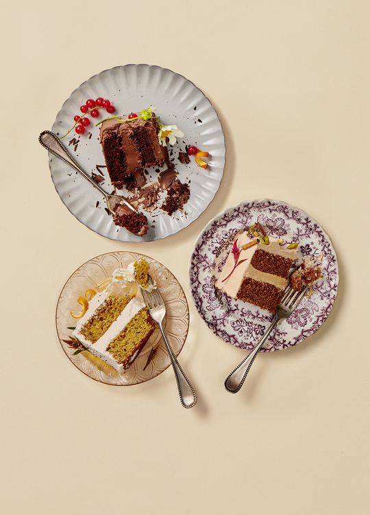 Three plates with slices of cake on a beige background