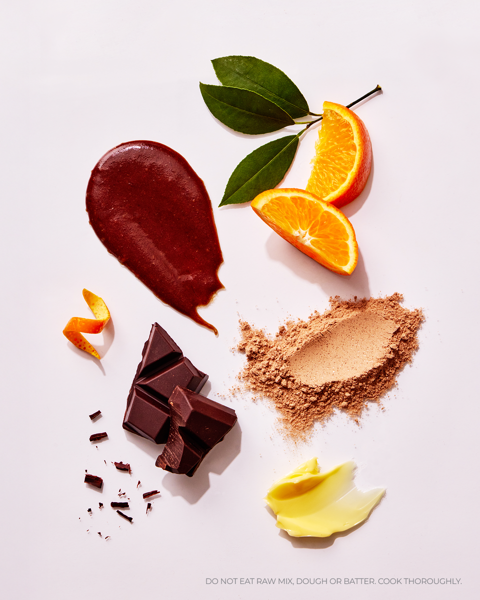 Raw ingredients including chocolate, orange slices, and a butter on a white background.