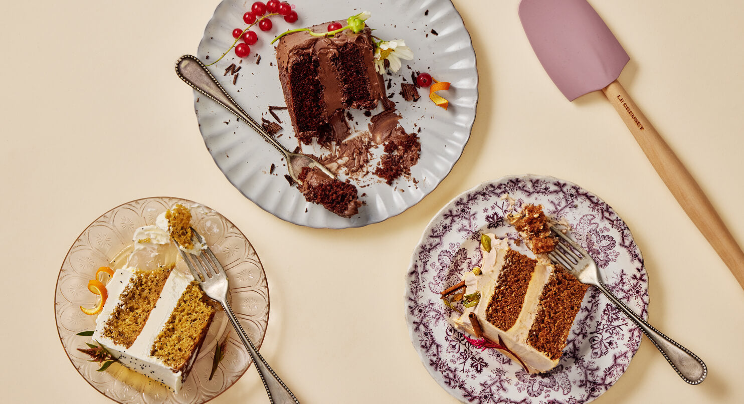 Three slices of cake on decorative plates with a spatula on a beige background