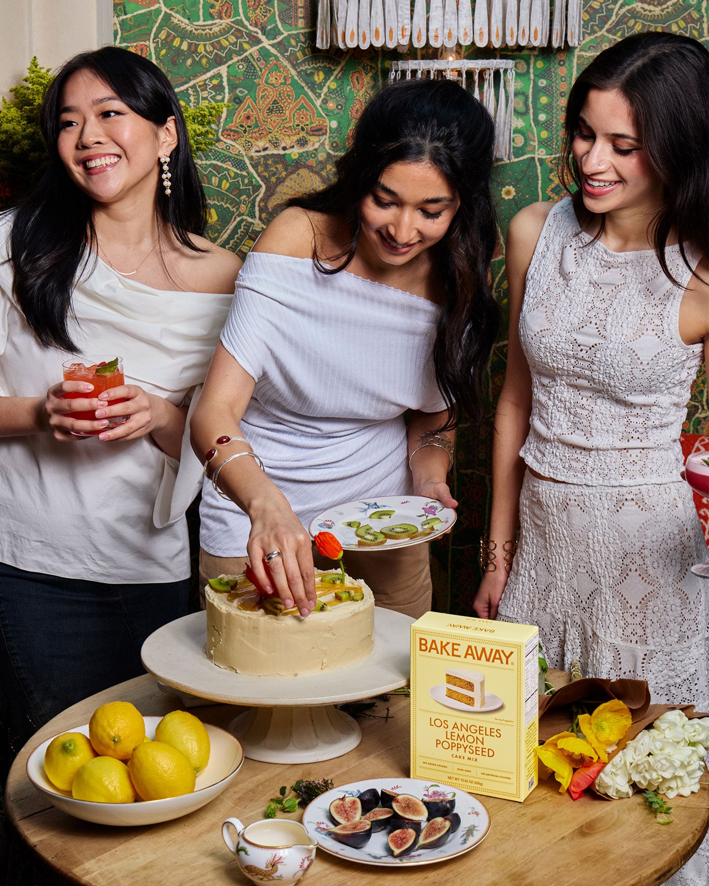Three women preparing a cake with a 'Bake Away' product in the background