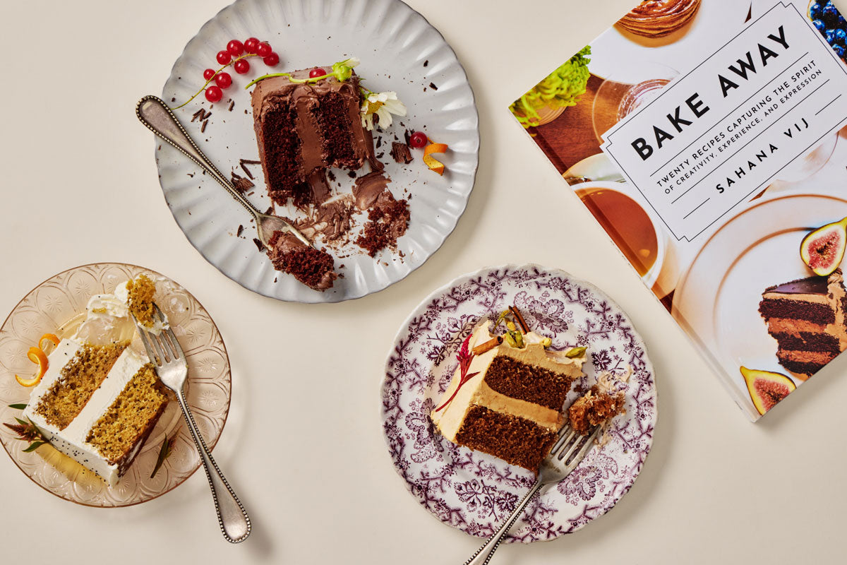 Three slices of cake on plates with a cookbook titled 'Bake Away' open to a page showing a cake.