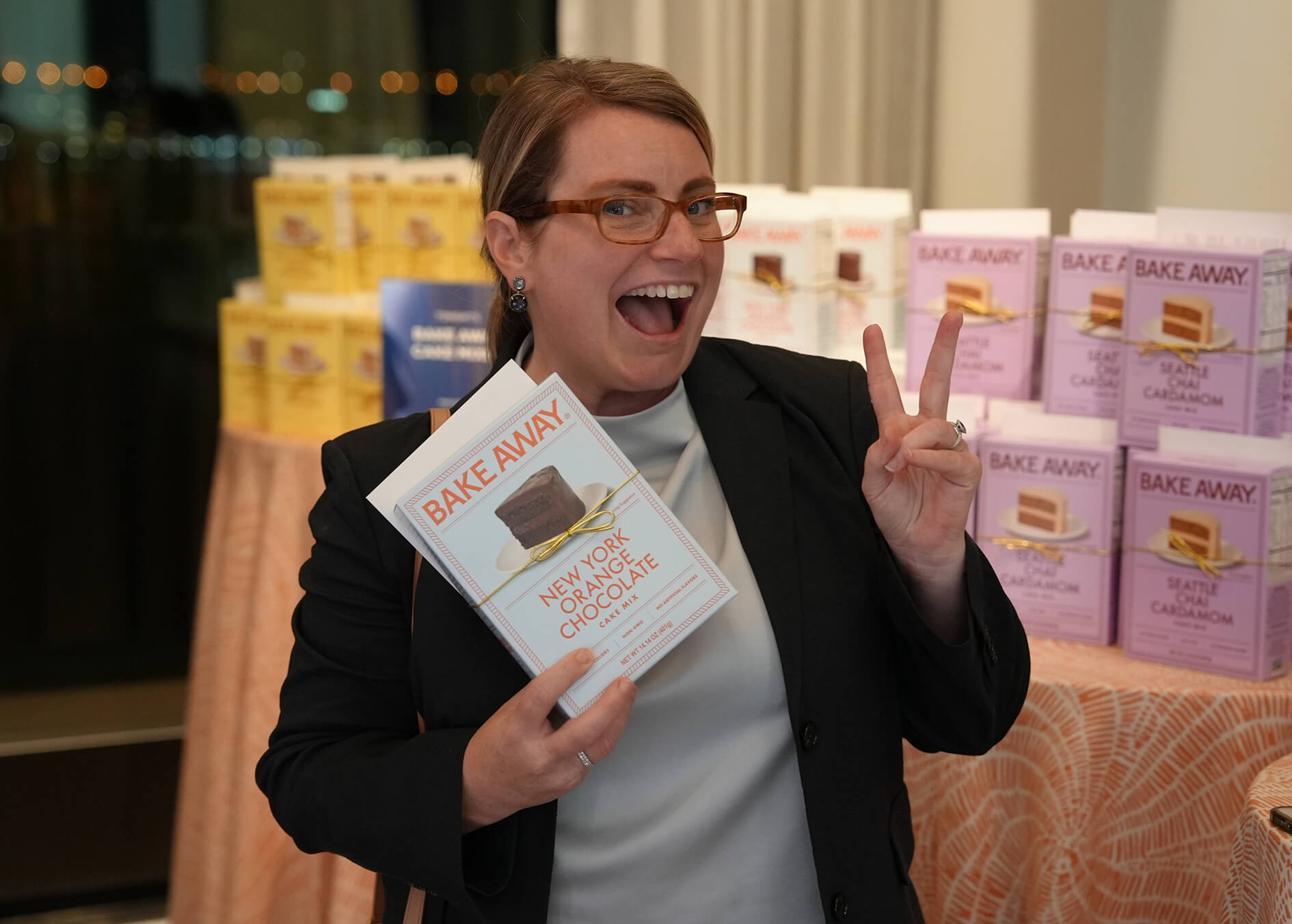 Woman holding a book titled 'Bake Away' with boxes in the background