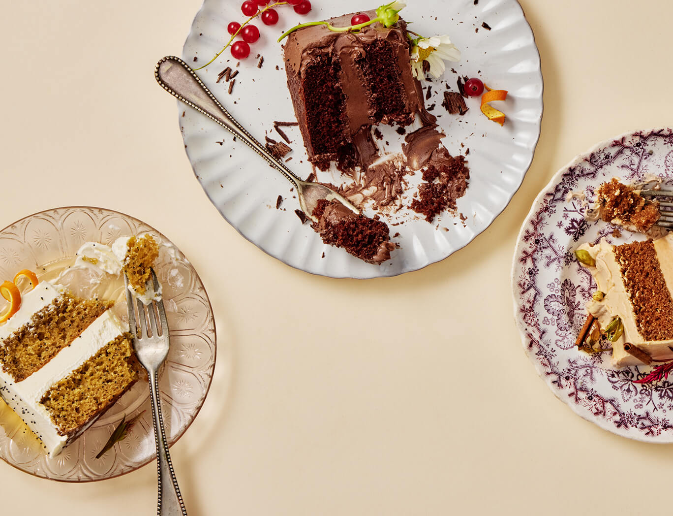 Three plates with slices of cake on a beige background